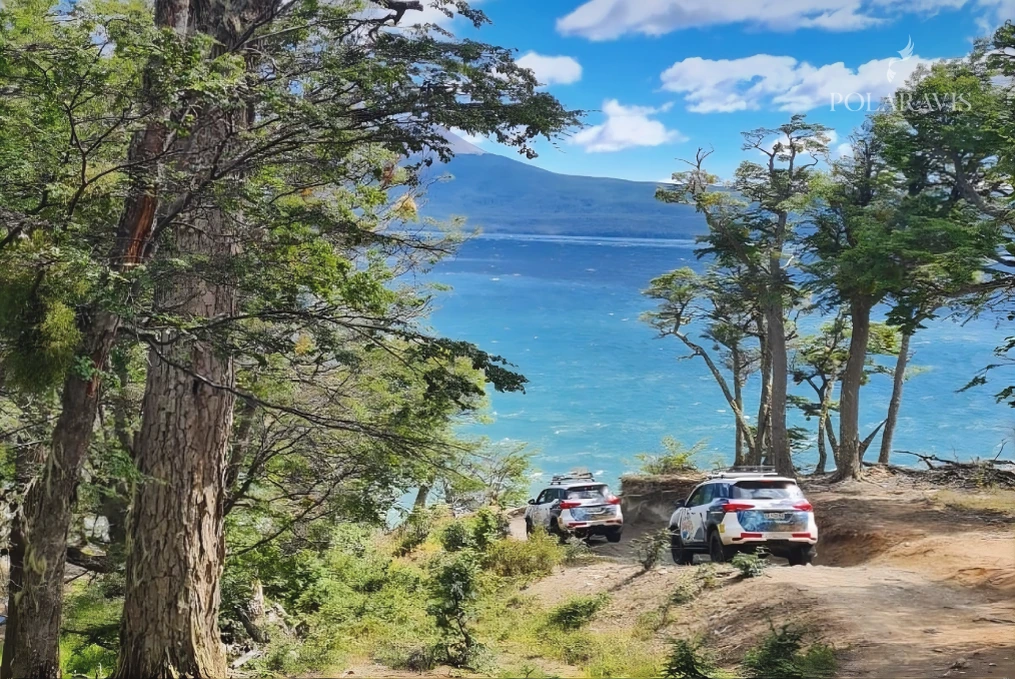 Camionetas 4x4 estacionadas sobre la costa del Lago Fagnano, de agua turquesa