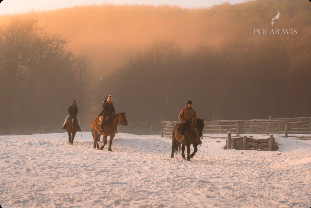 Caballos y jinetes junto al refugio de montana con luz de atardecer