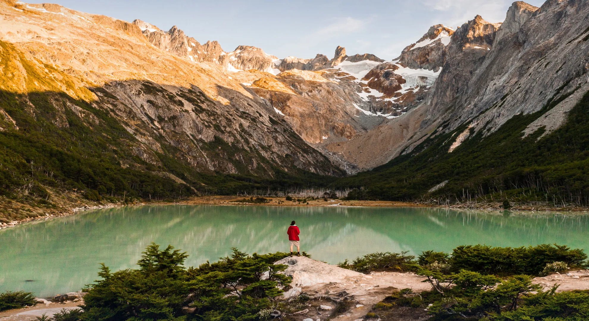 Caminante junto a una laguna de montana rodeada de cumbres