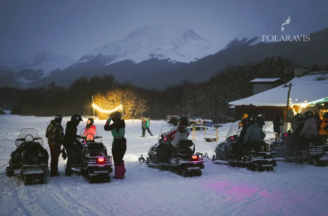Motos de nieve y luces al atardecer en la excursión nocturna