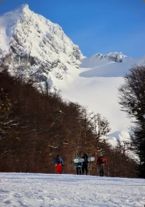 Grupo de caminantes sobre la nieve al pie de una montaña nevada en Ushuaia